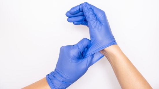 Closeup of blue gloves being put on a pair of hands
